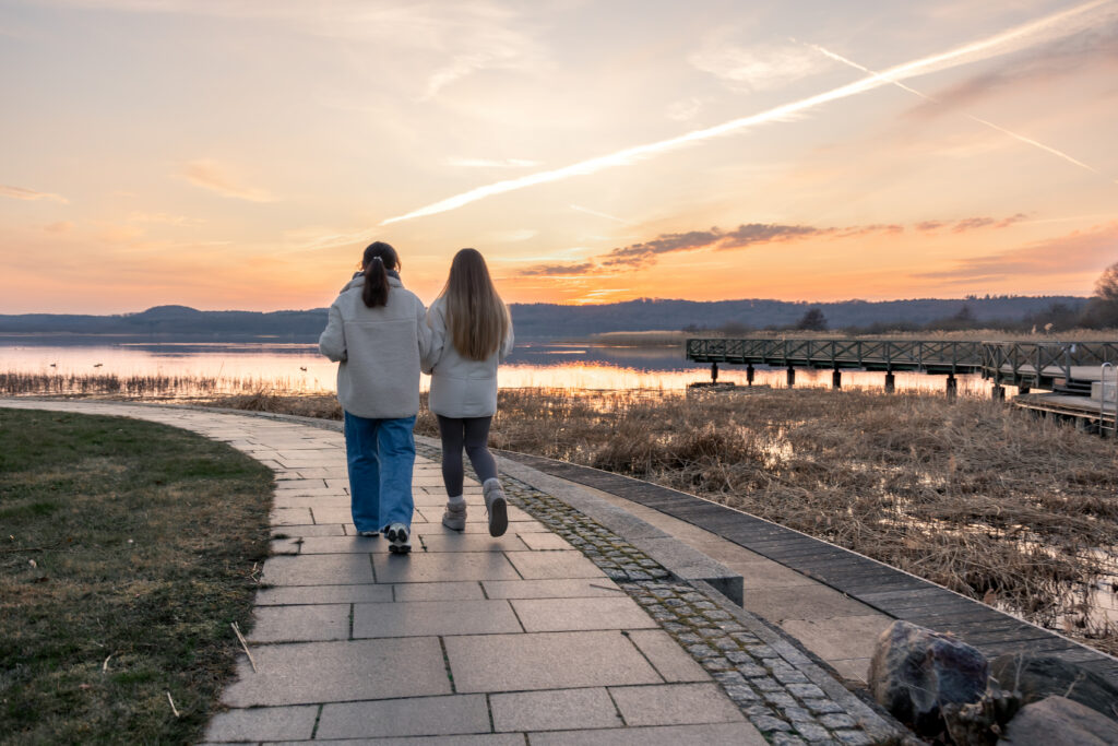 Zwei Menschen von hinten auf einem Weg am Wasser