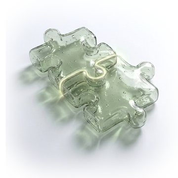 Zwei ineinandergreifende Puzzleteile aus salbeigrünem Glas
