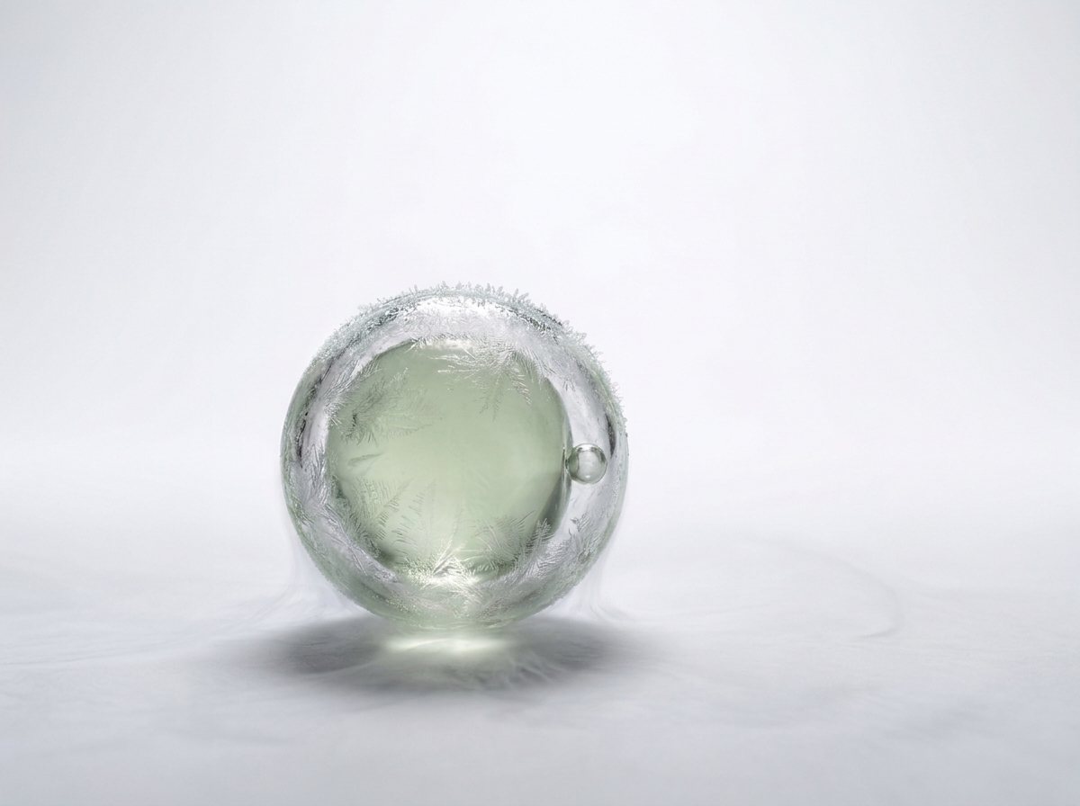 Eine Eizelle aus Glas mit feinen Eiskristallen auf der Hülle, als Bild für eine eingefrorene Eizelle