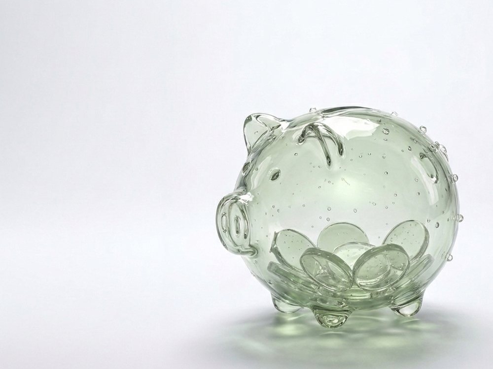 Sparschwein aus salbeigrünem Glas mit gläsernen Münzen im Inneren