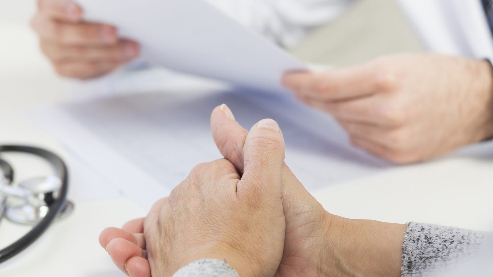 Patientin sitzt einer Ärztin gegenüber, beide sehen einen Befund an